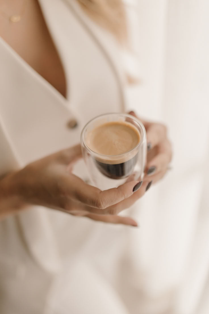 Person holding a glass of coffee with a blurred background